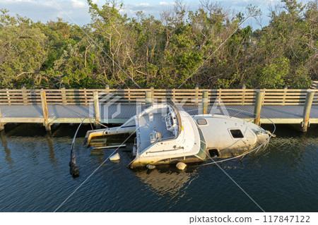 Aerial view of sunken sailboat on shallow bay waters after hurricane in Manasota, Florida 117847122