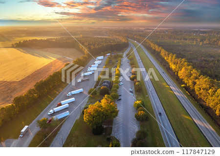 Aerial view of truck stop rest area near busy American interstate freeway. Recreational place during delivering cargo Aerial view of truck stop rest area near busy American interstate freeway. Recreational place during delivering cargo 117847129