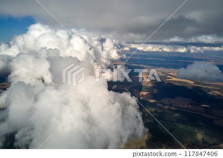 Aerial view from airplane window at high altitude of earth covered with white puffy cumulus clouds 117847406