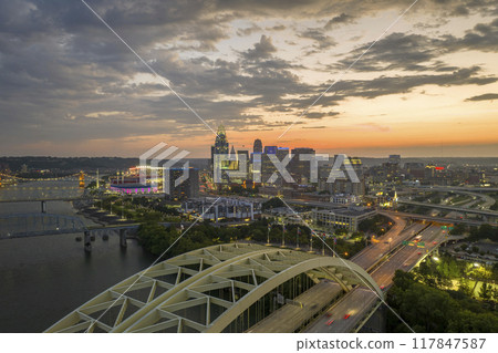 Highway traffic in Cincinnati, Ohio on Daniel Carter Beard Bridge with brightly illuminated high skyscraper buildings in downtown district. American city with business financial district at night Highway traffic in Cincinnati, Ohio on Daniel Carter Beard Bridge with brightly illuminated high skyscraper buildings in downtown district. American city with business financial district at night 117847587