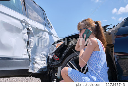 Sad female driver speaking on sellphone on street side calling for emergency service after car accident. Road safety and insurance concept 117847743