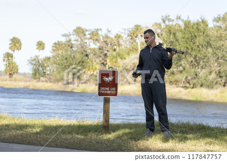 Operator is disappointed because he can not fly his quadcopter in national park no drone area. Man is unable to use his UAV near restriction notice sign 117847757