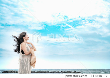 A woman wearing a straw hat by the beach 117848197