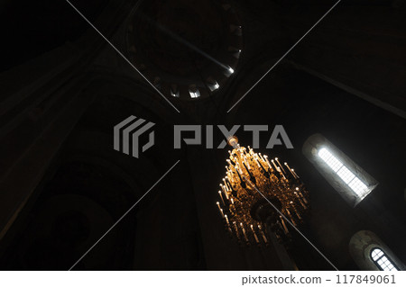 An Orthodox church dark interior with massive chandelier 117849061