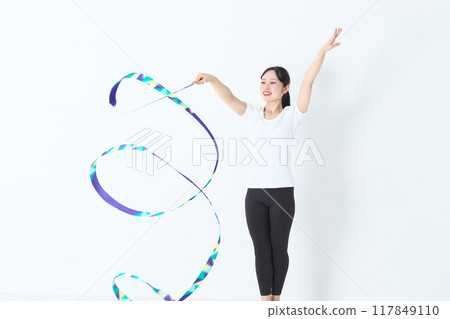 A woman in her twenties doing rhythmic gymnastics with a ribbon A woman in her twenties doing rhythmic gymnastics with a ribbon 117849110