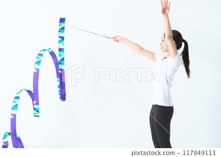 A woman in her twenties doing rhythmic gymnastics with a ribbon 117849113