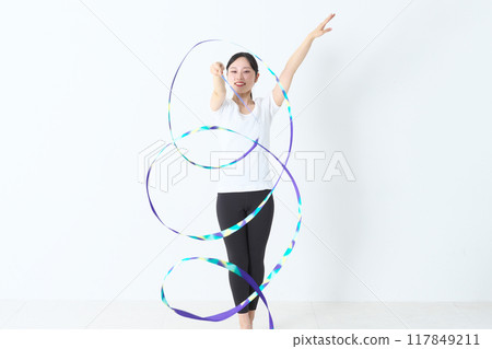 A woman in her twenties doing rhythmic gymnastics with a ribbon 117849211