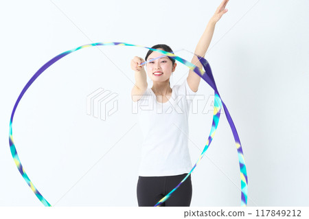 A woman in her twenties doing rhythmic gymnastics with a ribbon 117849212