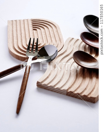 Everyday cutlery on a wooden coaster on a white background Everyday cutlery on a wooden coaster on a white background 117850165