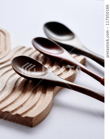 Everyday cutlery on a wooden coaster on a white background Everyday cutlery on a wooden coaster on a white background 117850166