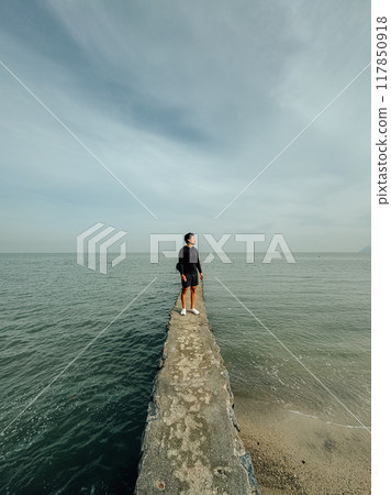 Man walking alone on the breakwater to see the view of the ocean. Man walking alone on the breakwater to see the view of the ocean. 117850918