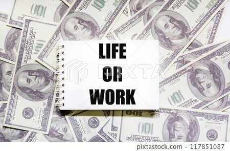 Symbol of life or work. Conceptual word "Life or work" on a notepad lying on dollars. Symbol of life or work. Conceptual word "Life or work" on a notepad lying on dollars. 117851087