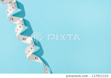 Measuring tape on blue background with copy space. Weight or length concept 117851310