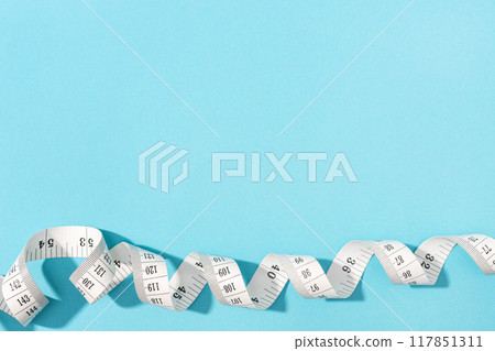 Measuring tape on blue background with copy space. Weight or length concept Measuring tape on blue background with copy space. Weight or length concept 117851311