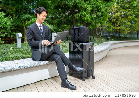 Male businessman typing on a computer while on the go Male businessman typing on a computer while on the go 117851686