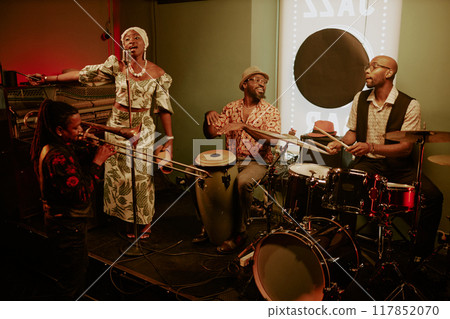 Wide shot of modern jazz band consisting of four members performing on stage in local bar Wide shot of modern jazz band consisting of four members performing on stage in local bar 117852070