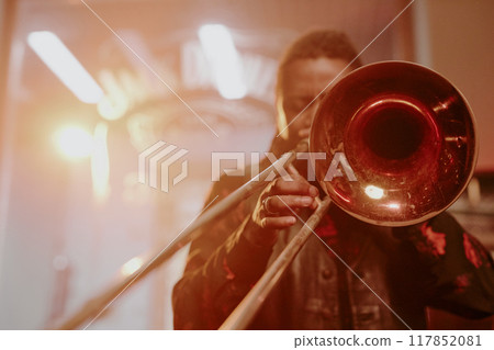 Unrecognizable African American male jazz musician playing trombone during performance, copy space 117852081