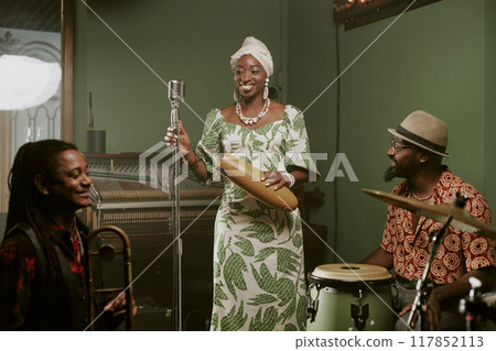 Cheerful male and female Black jazz musicians playing in band smiling while talking about new album during rehearsal Cheerful male and female Black jazz musicians playing in band smiling while talking about new album during rehearsal 117852113