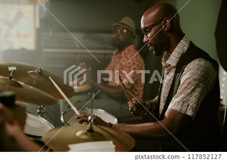 Side view shot of young Black man playing drums in modern jazz music band, copy space Side view shot of young Black man playing drums in modern jazz music band, copy space 117852127