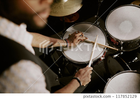High angle view of unrecognizable Black man holding drumsticks sitting at drum kit, copy space 117852129