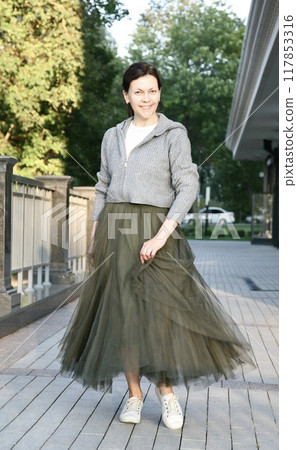 Middle aged woman in fashionable green tulle skirt smiling and twirling 117853316