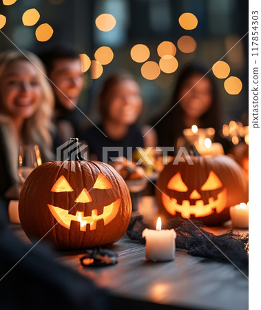 Friendly Group Celebrating Halloween with Jack-o-Lanterns and Candlelit Dinner 117854303