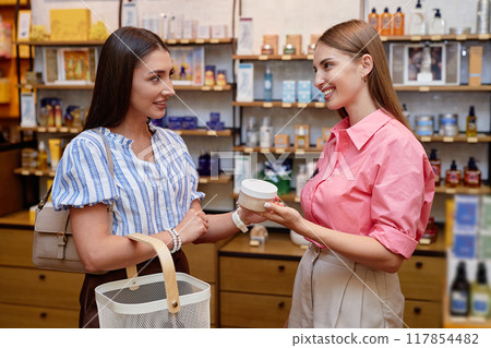 Shop assistant and customer holding salt scrub together Shop assistant and customer holding salt scrub together 117854482