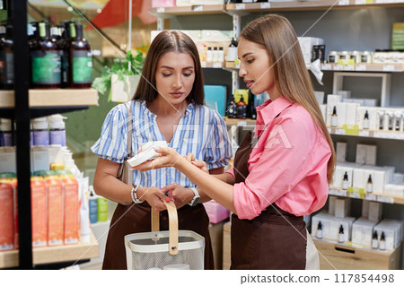 Female shop assistant showing cream tester to customer Female shop assistant showing cream tester to customer 117854498