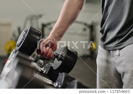 Medium close up of unrecognizable male hand holding heavy rubberized dumbbell 117854603