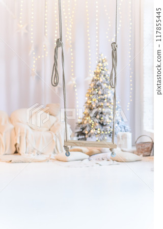 Decorative wooden swing at white cozy interior with Christmas decorations on background. 117855445