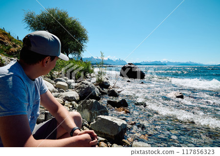 Young man on a beautiful sunny day on the shore of a lake Young man on a beautiful sunny day on the shore of a lake 117856323