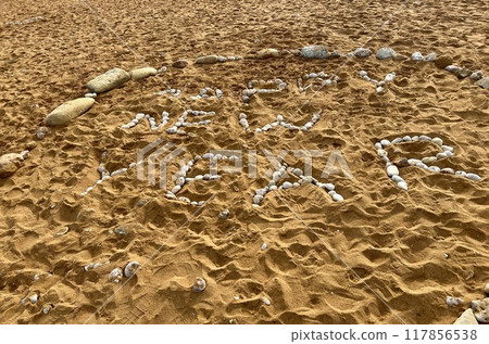 Inscription Happy New Year made with stones on the sand on the seashore 117856538