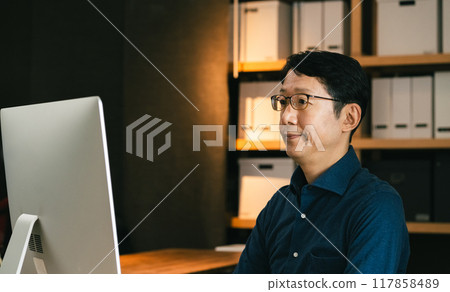 Middle-aged man facing a computer Middle-aged man facing a computer 117858489