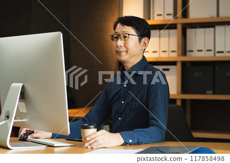 Middle-aged man facing a computer Middle-aged man facing a computer 117858498