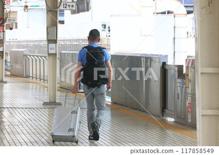 Passengers walking along the Shinkansen platform with suitcases. Travelers at Tokyo Station. Shinkansen platform. 117858549