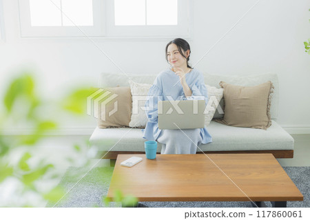 A woman using a computer in the living room 117860061