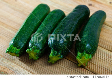Closeup of fresh zucchini with chopped slices on wooden surface Closeup of fresh zucchini with chopped slices on wooden surface 117860116