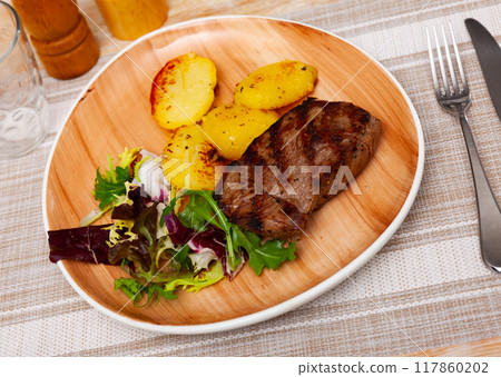 Tasty homemade grilled beef tenderloin steak, fried potato and salad with arugula 117860202