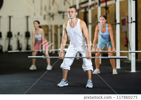 Athletic man doing squats with barbell in gym Athletic man doing squats with barbell in gym 117860275