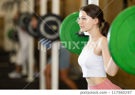 Young woman lifting barbell in gym 117860297