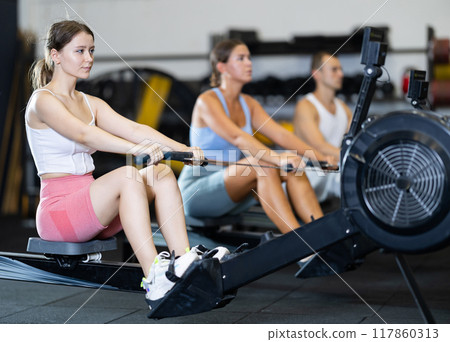 Young woman exercising on rowing machine 117860313
