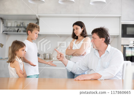 Angry parents scolding two children standing in front of them Angry parents scolding two children standing in front of them 117860665