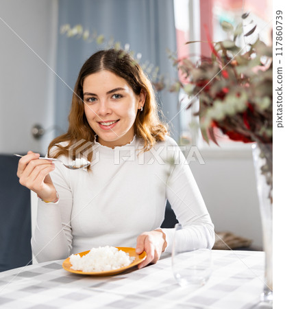 Emotional young woman eating rice at home Emotional young woman eating rice at home 117860739