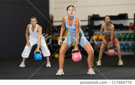 Young woman lifting kettlebell in gym Young woman lifting kettlebell in gym 117860776
