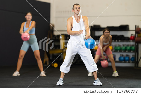 Young man training with kettlebell in gym Young man training with kettlebell in gym 117860778