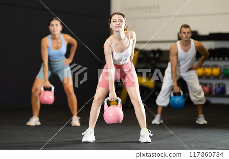 Young woman lifting kettlebell in gym Young woman lifting kettlebell in gym 117860784