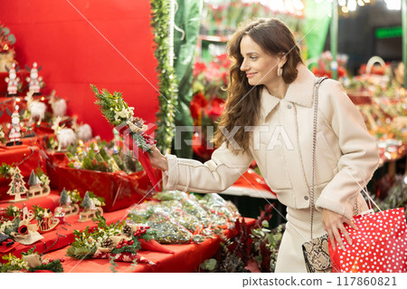 Cheerful woman looking for New Year decorations in street market Cheerful woman looking for New Year decorations in street market 117860821