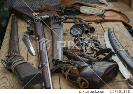 Set of antique firearms on wooden table. Rifles, bayonets, saber, peak tips, selective focus. 117861328