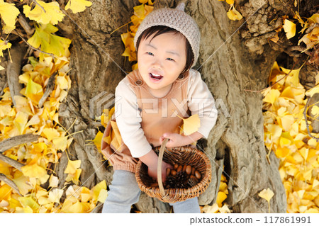 一個 1 歲的孩子在秋季公園玩橡子和松果 117861991