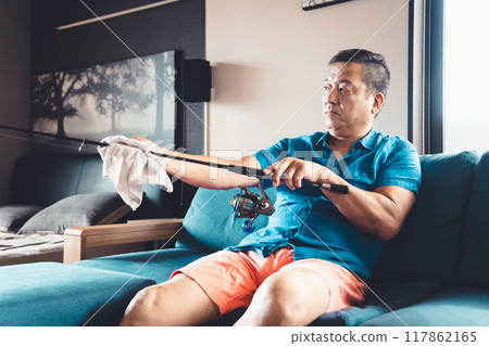 一名男子於假期在家中維護釣魚竿 一名男子於假期在家中維護釣魚竿 117862165